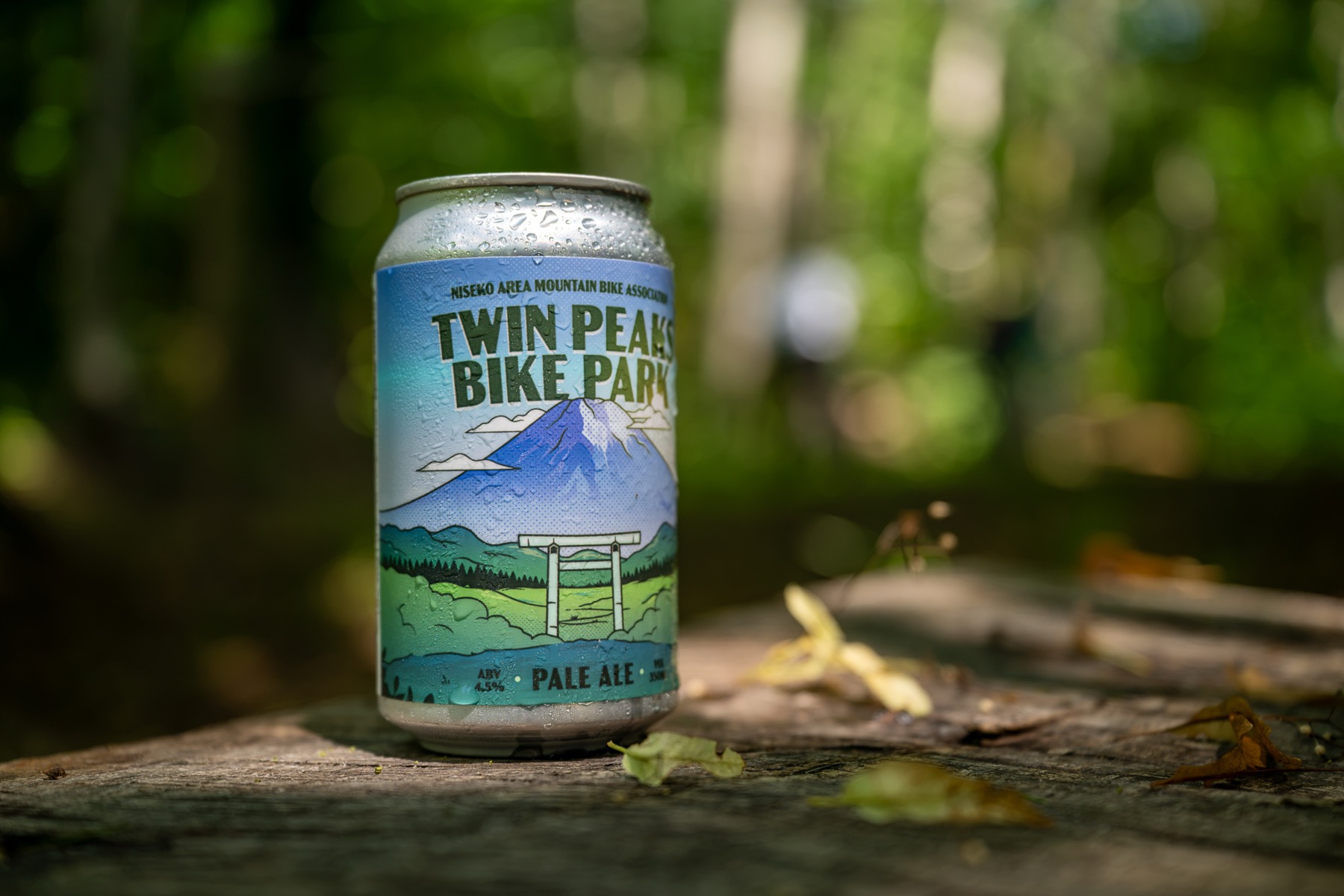 Twin Peaks Bike Park Pale Ale can on a mossy log in the Niseko forest
