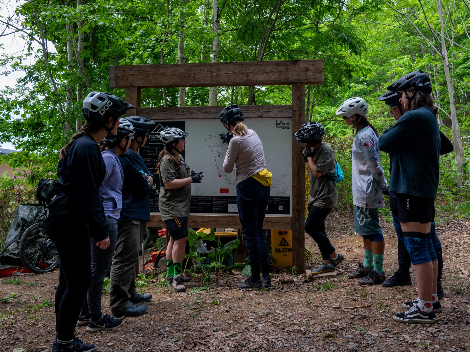 Dirty Dames riders gathered around a Niseko trail map at the trailhead before a group ride