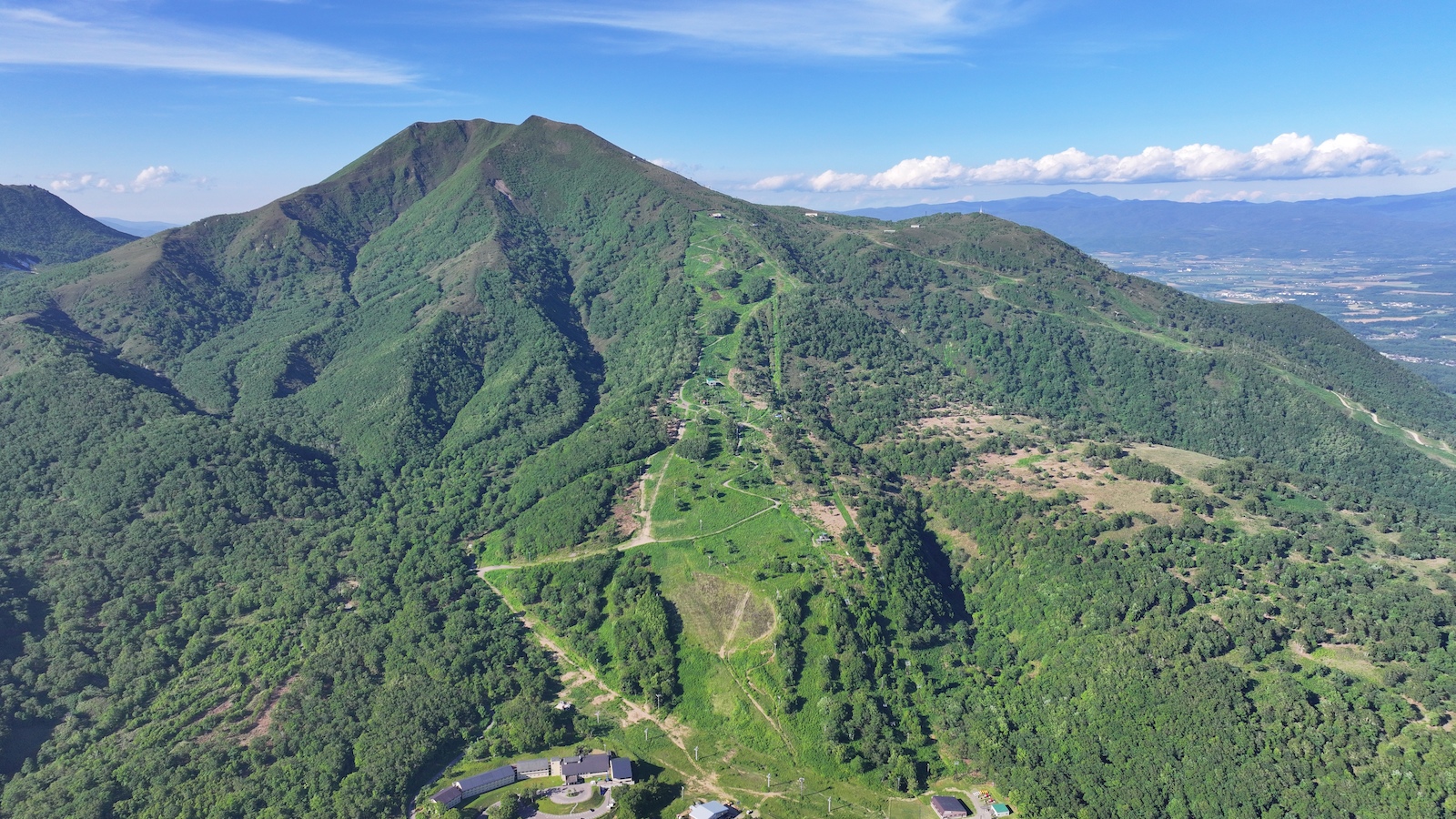 Aerial panorama of Annupuri's peak with ski runs and forested ridge stretching across the Niseko range