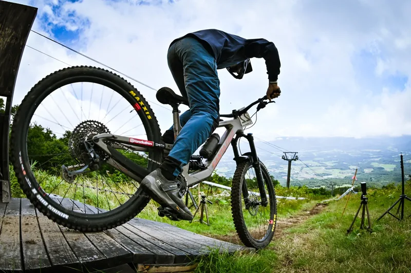 A rider rolling off a wooden feature near the top of the Annupuri course, lift towers behind