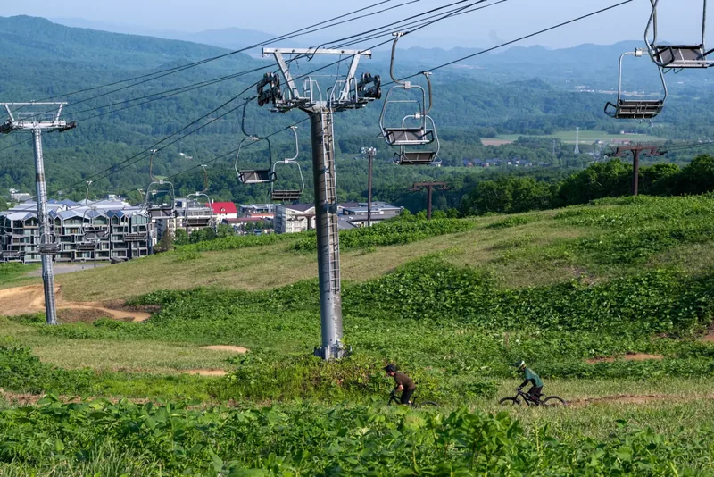 Grand Hirafu chairlift descending toward Hirafu Village with riders on the lower trails