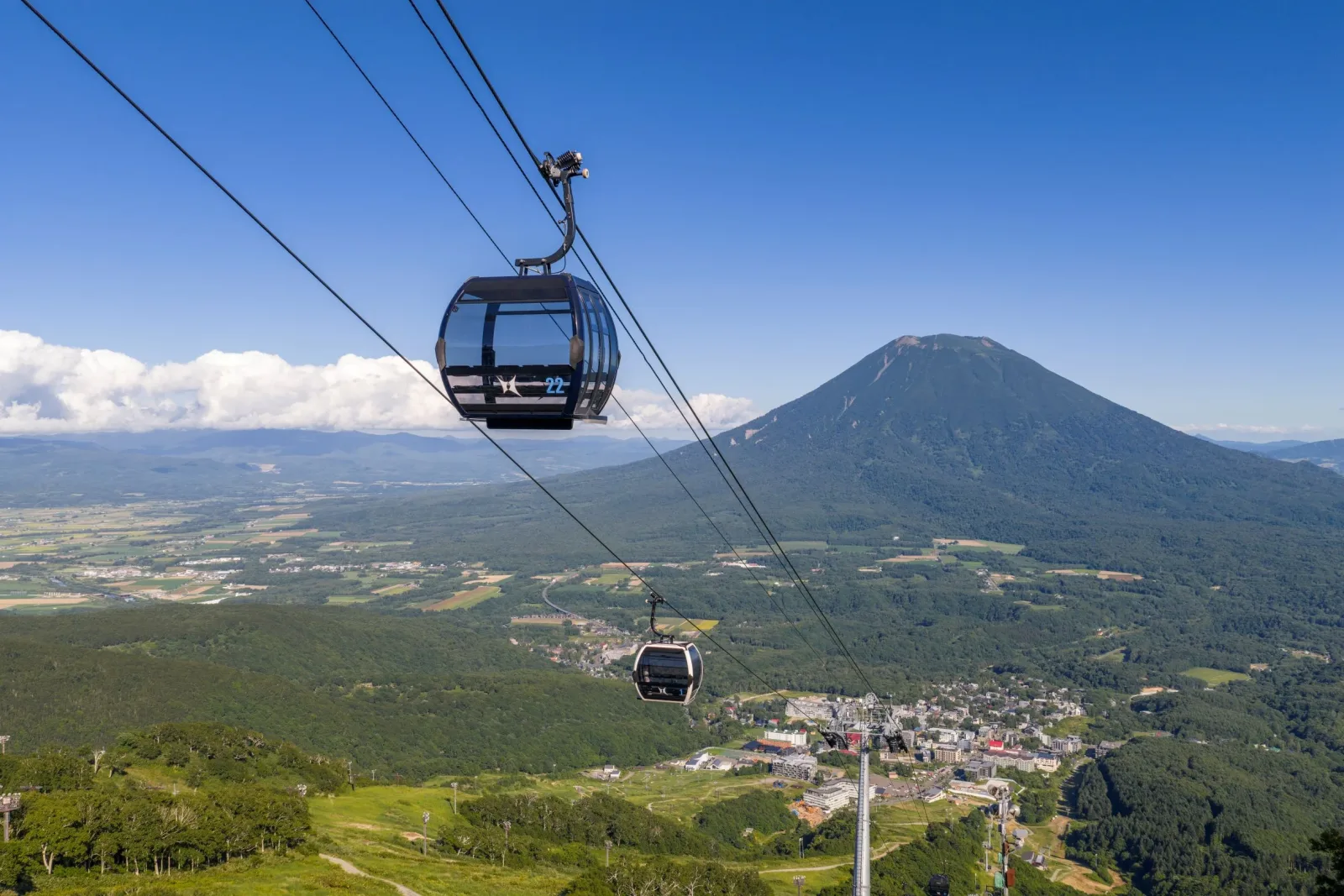 Grand Hirafu gondola cabins suspended over the Niseko valley with Mount Yotei in the distance