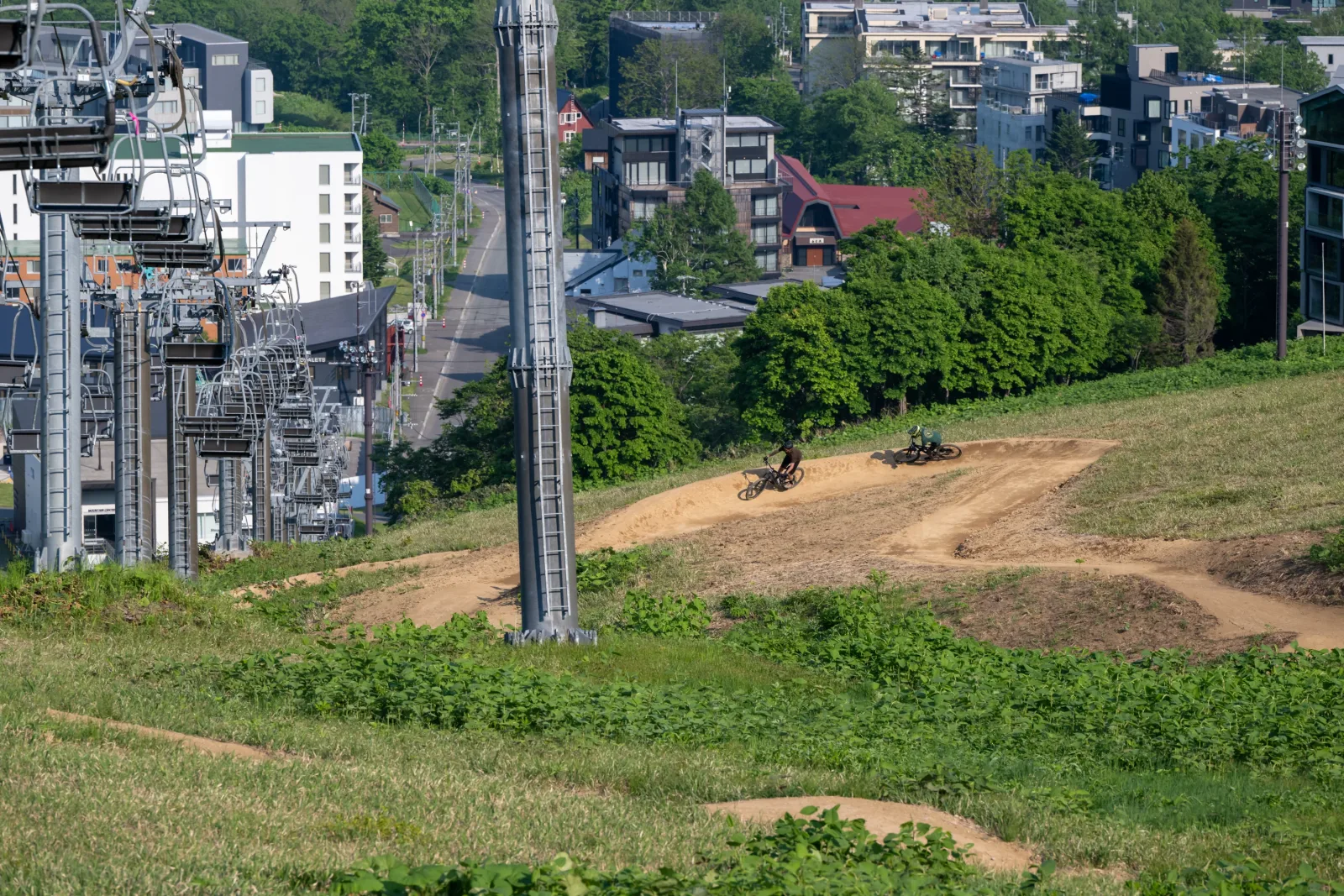 Riders on the lower jump trails at Grand Hirafu with Hirafu Village in the background